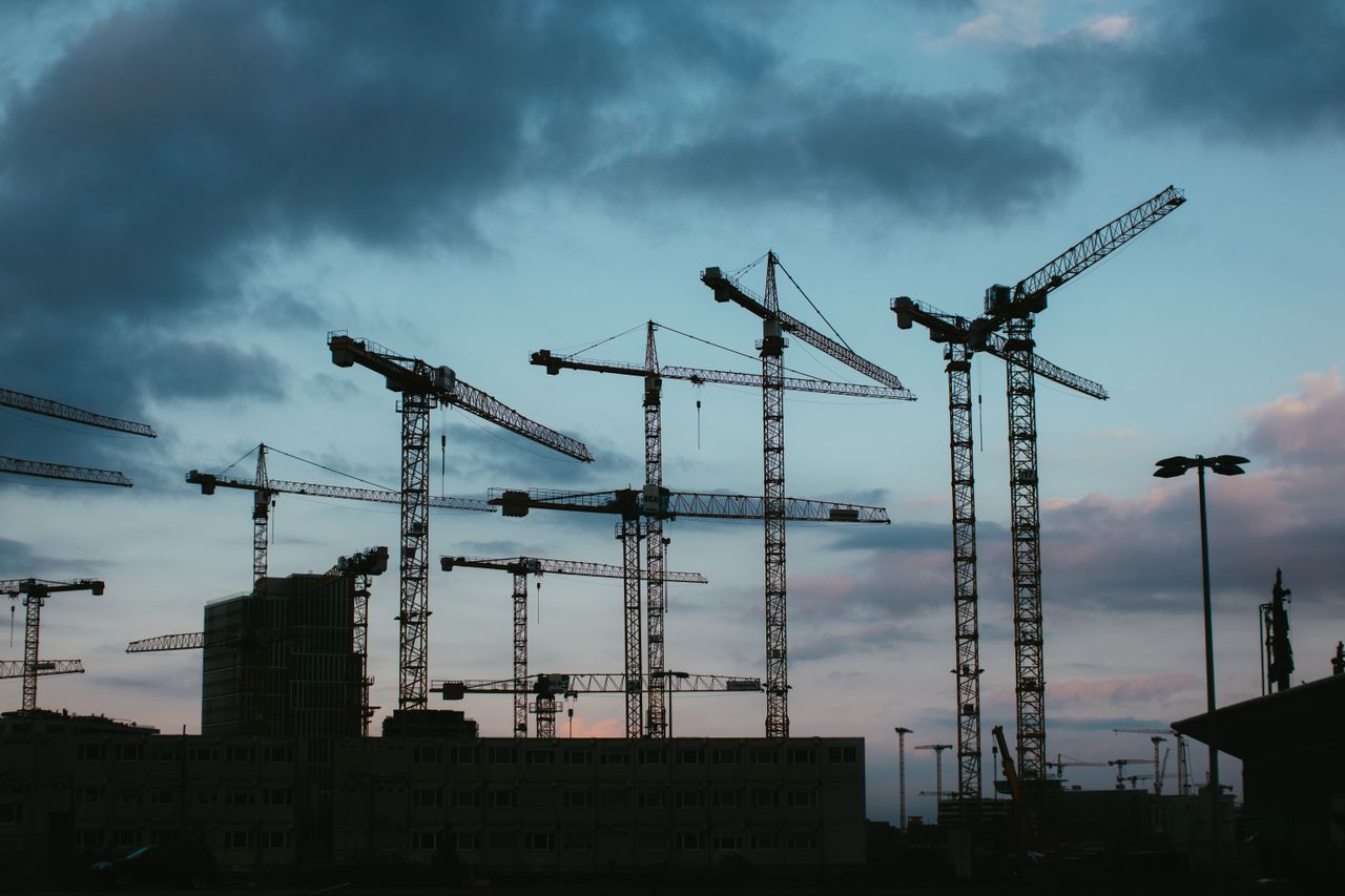 services-01 Multiple construction cranes silhouetted against the evening sky, capturing industrial progress.